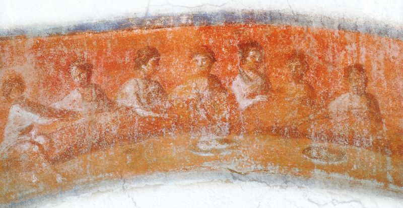Early Christian fresco from the Catacomb of Priscilla showing seven figures seated at a table with bread and fish in a eucharistic meal