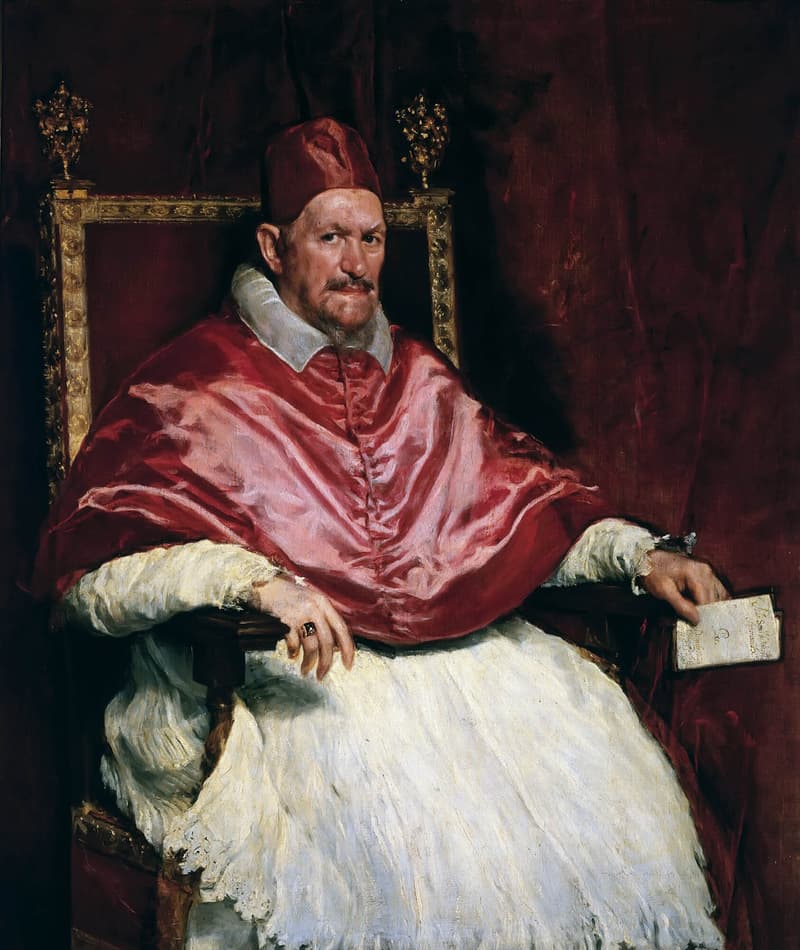 Diego Velázquez’s 1650 portrait of Pope Innocent X, seated in red cape and cap against a crimson curtain, holding a folded petition