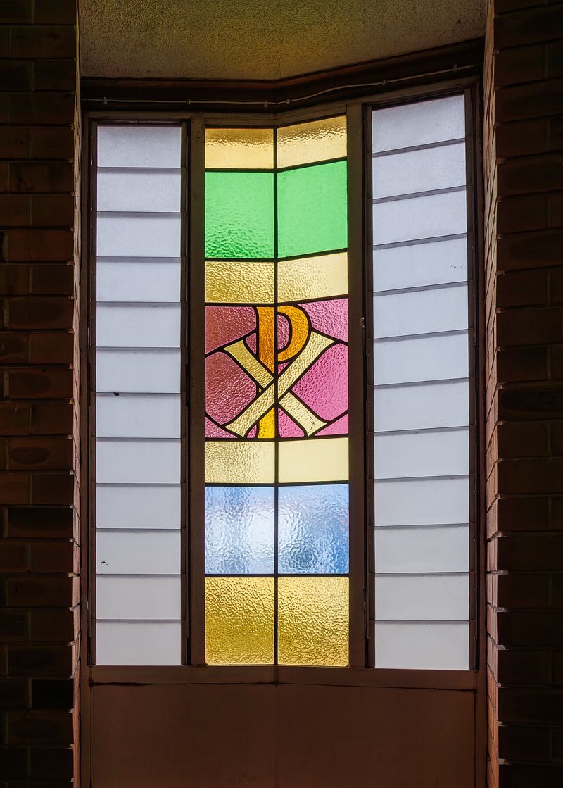 Stained-glass window featuring the Chi-Rho (XP) Christogram, the ancient Greek monogram for Christ that gave us 'X' as shorthand for Christ in 'Xmas'