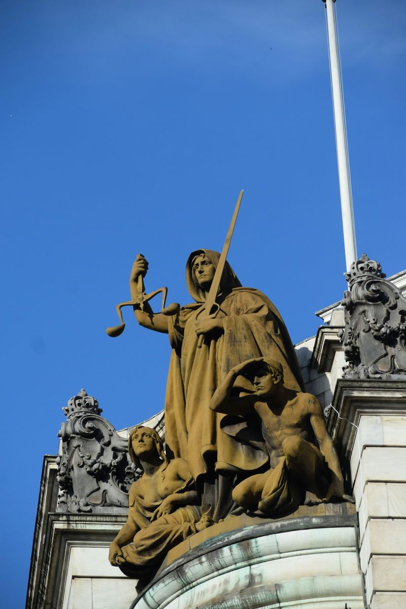 Statue of Lady Justice holding scales and sword against a blue sky