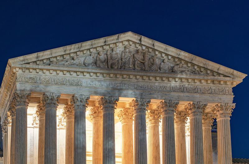 West pediment of the United States Supreme Court Building at dusk, with the inscription EQUAL JUSTICE UNDER LAW carved into the architrave above the columns