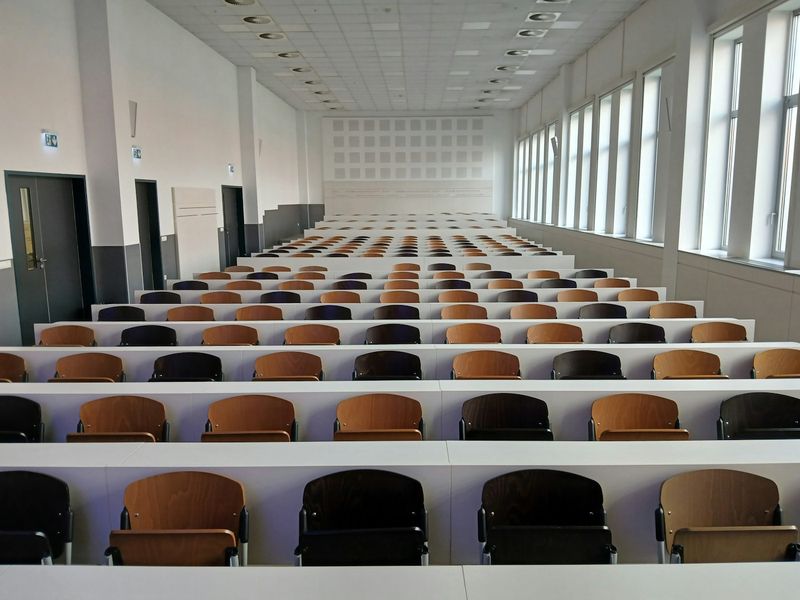 An empty university lecture hall with rows of seats, awaiting students