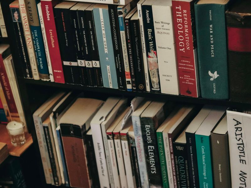 A bookshelf filled with a variety of theology and religious-studies volumes, evoking the breadth of sources a comparative theologian engages
