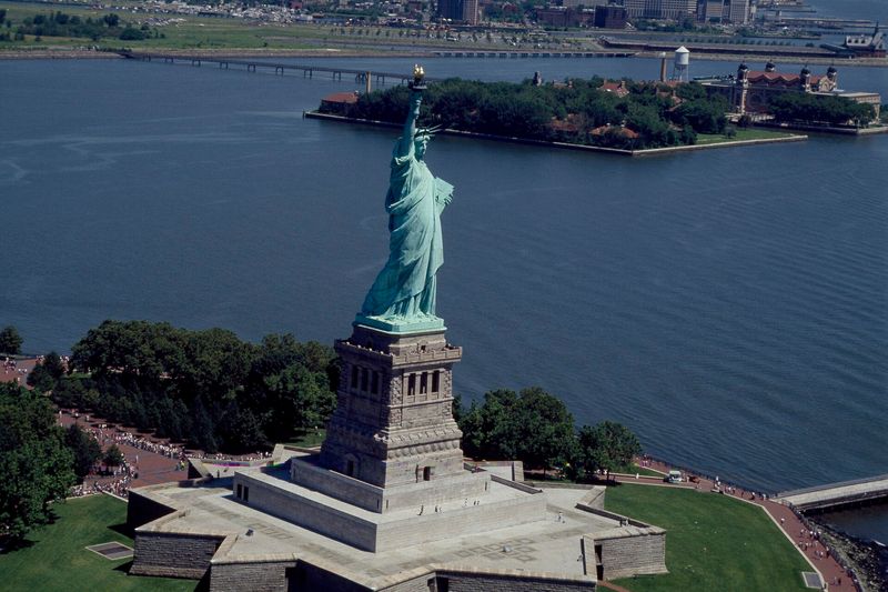 Aerial photograph of the Statue of Liberty with Ellis Island in the background — the iconic gateway for non-citizen arrivals, fitting context for the Qualified Domestic Trust, the estate-planning vehicle that preserves the marital deduction when a surviving spouse is not a U.S. citizen.