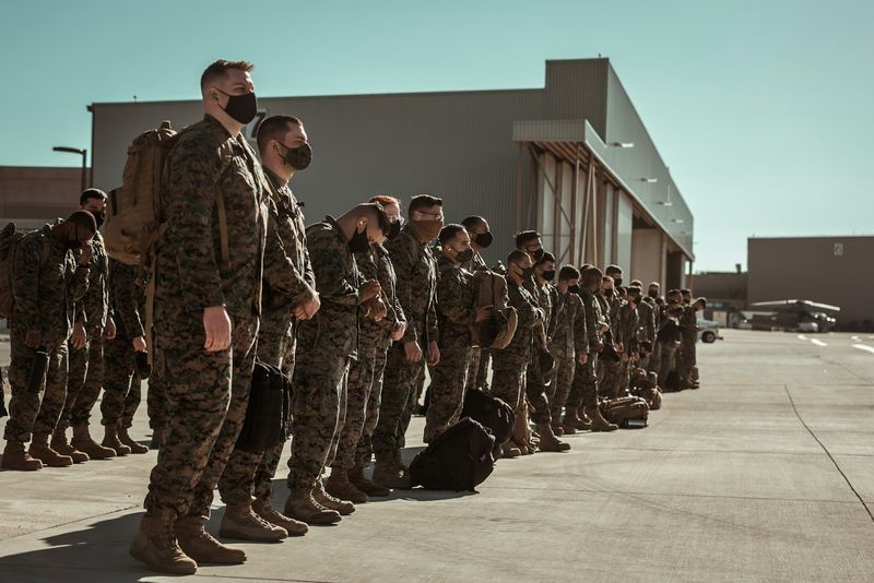U.S. Marines in camouflage utilities standing in formation on a flight line