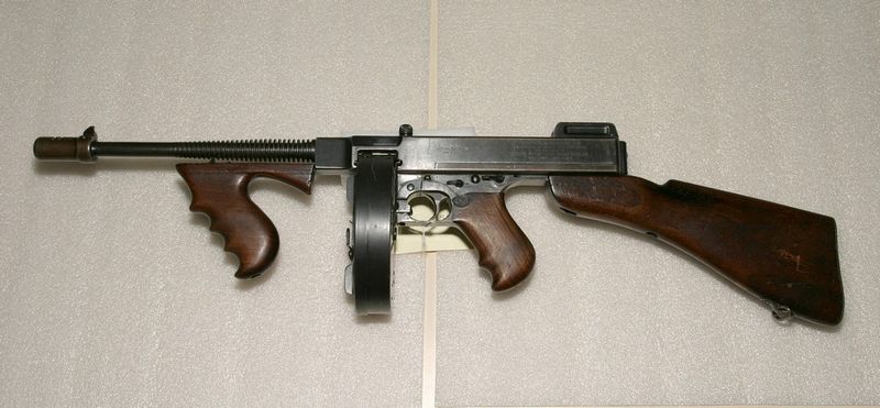 A Thompson submachine gun (M1928) with a drum magazine, displayed at Alcatraz — the iconic weapon whose proliferation drove enactment of the 1934 National Firearms Act, the federal statute that defines Title II weapons.